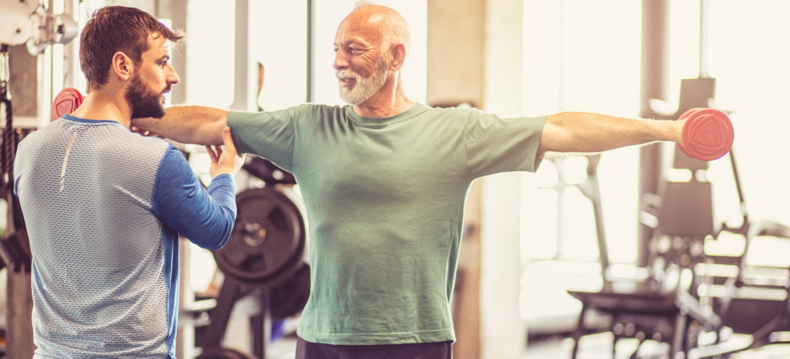 Senior man doing exercises under supervision of a trainer in Cypress community.