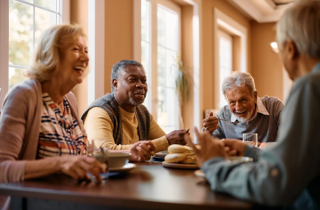 A group of older adults enjoying a meal together around a table, laughing and smiling.