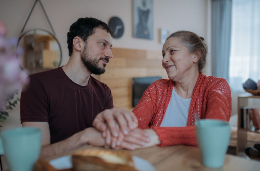 An adult child holds their parent's hands and comforts them, practicing empathetic communication.